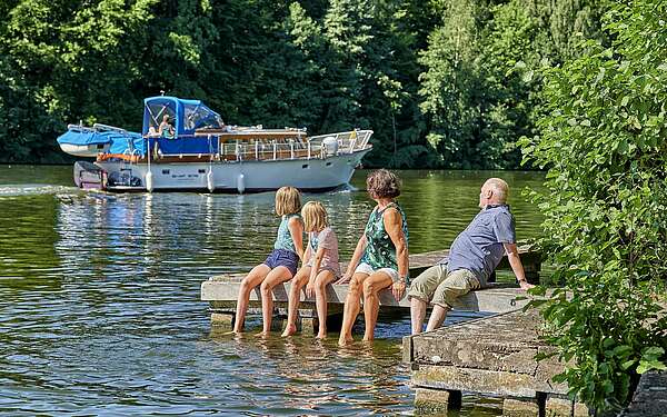 Familie sitzt auf Steg